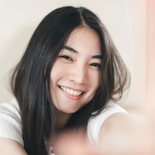 White ribbed sweater with black hair and smiling face.